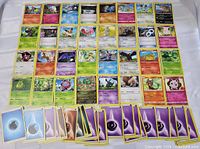 Top view of assorted Pokemon cards laid out in rows showing various Pokemon such as Eevee, Piplup, and others with several energy cards at the bottom.