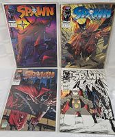 Four Spawn comic books shown in protective sleeves, arranged in a square view.