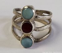 Front view of sterling silver ring with three bezel-set round stones (two blue, one red) in triple-band design.