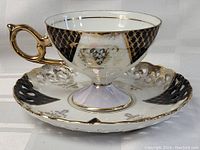 Tea cup and saucer set showing the cup's side view highlighting the gold handle and decorative patterns.