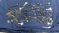 Assorted vintage skeleton keys and modern keys on a dark cloth background showing quantity and variety.