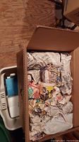 Box filled with individually wrapped Christmas decorations in newspaper.