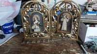 Set of two carved gold framed paintings of female saints on workbench