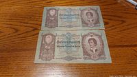 Front side of two 1932 Hungarian 50 Pengo banknotes showing portrait of a woman and printed denomination.