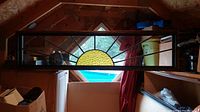 Full-length view of the rectangular stained glass panel leaning against attic shelving