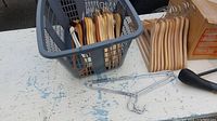 Wooden and steel hangers shown in plastic basket and separately.