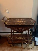 Front right angle view showing two-tier cart with decorative top and bottom trays, turned wood posts, brass spoked wheels and bottle holders