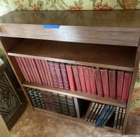 Photo of wooden bookshelf with two shelves filled with many hardcover books. Shelf measures 36 x 9 x 36 inches.