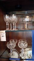 8 crystal wine glasses and 4 crystal coup glasses displayed on shelves along with the pedestal serving dish with lid showing its shape and size.