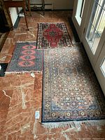 Three rugs displayed on marble floor: large runner and two small accent rugs