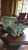 Overall left-side view of jade carriage and horses on wooden base against living room background
