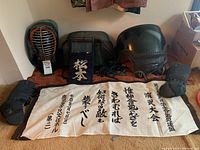 Kendo armor components including men, dou, tare, kote, and banner displayed on floor.