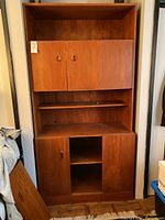 Front view of closed upper cabinet doors and visible lower cabinet door and shelf area.