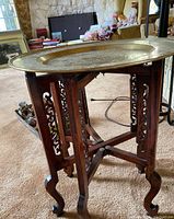 Assembled table with brass top on carved wooden base, showing overall appearance and proportions