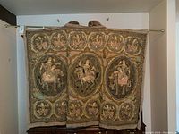 Full frontal view of the tapestry showing its size and detailed embroidery of figures seated on animals within large and smaller circular frames.