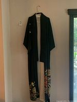 Full frontal view of black silk kimono hung on hanger