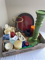 Entire lot photo showing assorted candles, wooden green candle holder, brass stand, and Party Lite plate in a cardboard box.