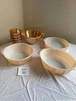 Three Fire-King casseroles and mixing bowl on table, alongside four amber glass candle holders