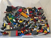 Plastic bin containing assorted Lego pieces of multiple colors and shapes.