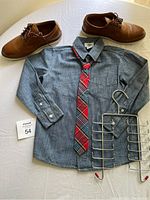 Full view of all items: denim shirt with tie, leather shoes, and metal rack.