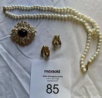 Full set: pearl necklace, gold-tone brooch with dark center stone, matching clip-on earrings, and bracelet.