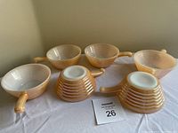 Set of six Fire-King bowls displayed with handles visible, showing the ribbed peach luster exterior and white interior.