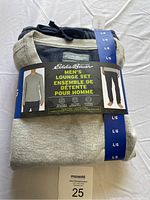 Eddie Bauer men's lounge set, thermal shirt and fleece pants folded with packaging showing brand, size, and product info.