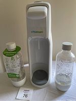Front view of white Sodastream Jet soda maker with two bottles placed beside it, one bottle has a label and the other has bubble graphics.
