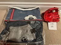 Soccer bag still packed in clear plastic, showing blue and red Louis Garneau soccer bag with soccer ball image and a cotton towel inside a mesh pocket. Red Wilsons Mini-Pro baseball glove resting next to the bag