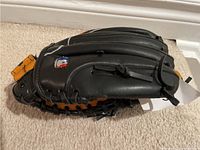 Wilson black and tan genuine leather baseball glove, showing external side with logo patch.