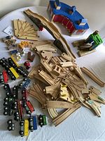 Wide view of assorted wooden train tracks, trains, people, and accessories laid out on table
