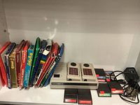 Intellivision II console with two numeric keypad controllers, power adapter, and several game cartridges visible.