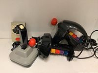 Five ColecoVision controllers arranged, showing two joysticks, two Super Action Controllers with numeric keypads, and a Commodore Top joystick.