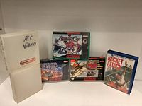 Four Super Nintendo game boxes and universal Nintendo plastic cases, including Populous, Stanley Cup, Super Black Bass, and Racket Attack games.