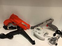 Lot overview showing two gaming zapper guns and a Sega Dreamcast controller against a white background.