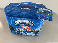 Photo of closed blue Skylanders carrying case with handle and character graphics