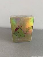 Front view of sealed holographic gold Pokemon card deck featuring Pikachu with detective hat illustration.