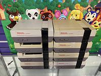 Eight stacked Nintendo NES consoles showing external condition with three units noticeably dirtier and with wear.