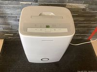 Front view of white Frigidaire dehumidifier on floor, control panel illuminated showing humidity at 45%