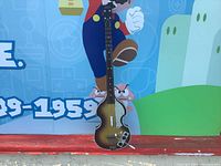 Full front view of the guitar controller against a colorful backdrop, showing the sunburst effect and shape of the guitar.