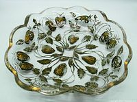Top view of clear glass dish with gold painted strawberry and leaf motif, showing scalloped edges and detailed intaglio pattern.