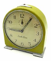 Front view showing yellow repainted metal clock case, off-white dial with black numbers and hands, 'Smith Alarm' branding on face.