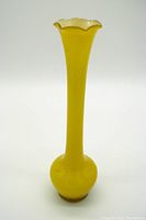 Front view of tall yellow art glass bud vase showing bulbous base and scalloped flared rim.