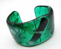 Front side view of green fused glass cuff bracelet showing vibrant green jewel tone and fused black geometric shapes inside.