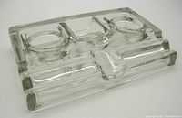 Angled side view showing the raised edges and two circular wells for ink, along with pen rests.