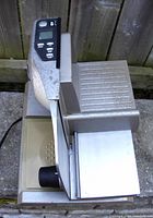 Side angle showing the digital control panel, blade housing, and food tray. Visible wear and surface scratches on the unit.