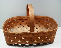 Wide view of the basket showing woven split wood construction, handle, and rectangular shape.