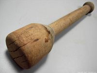 Close-up photo showing the rounded masher end with visible cracks and wood grain details.