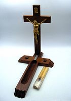 Photo showing crucifix with foldout base unfolded and sealed candle package beside it