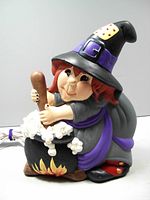 Full side view of ceramic witch figurine stirring a bubbling cauldron, not lit.